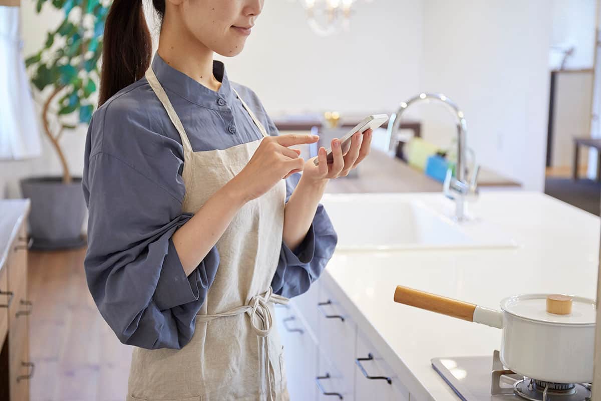 キッチンでスマートフォンを操作する女性